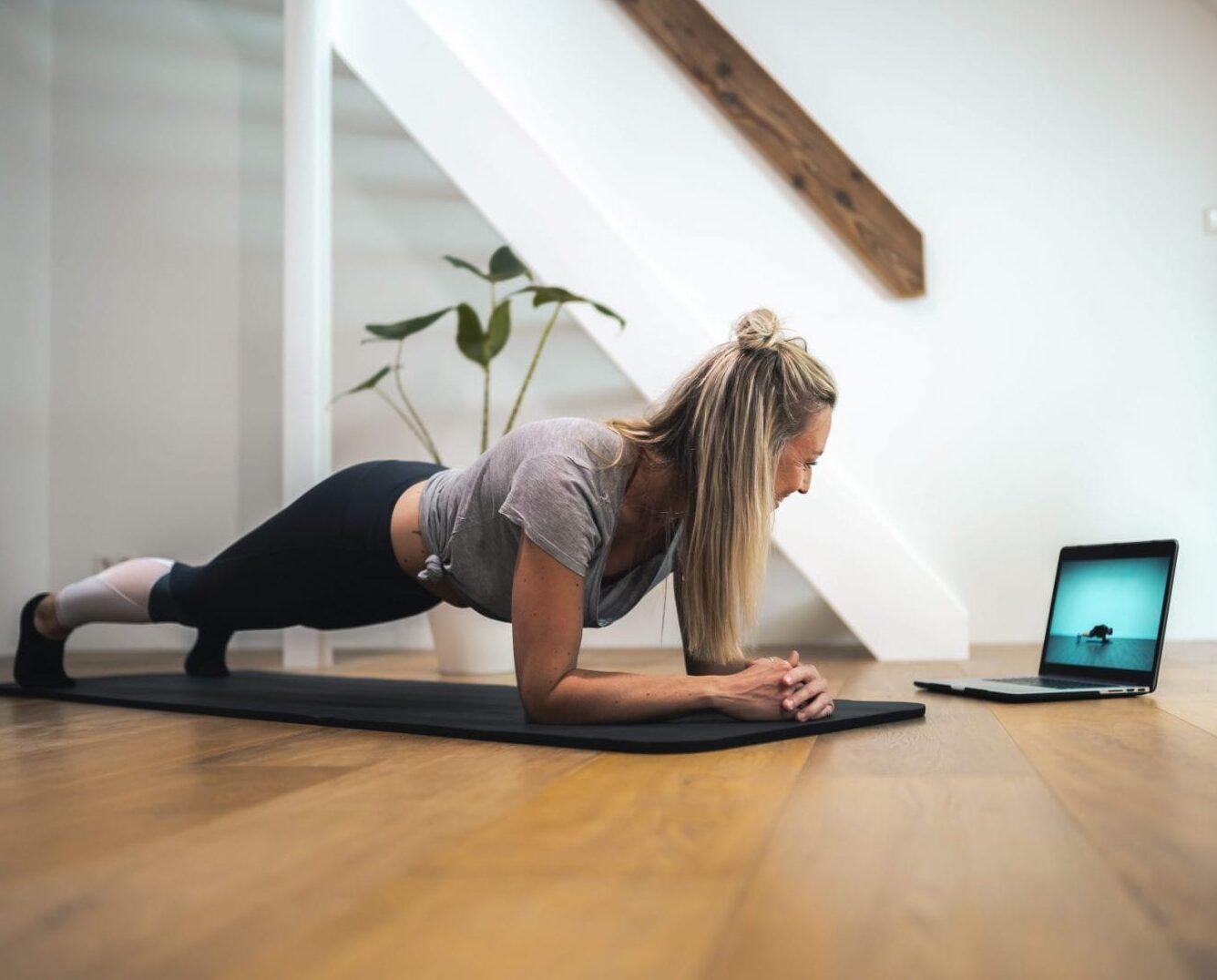 vrouw doet plank bij laptop